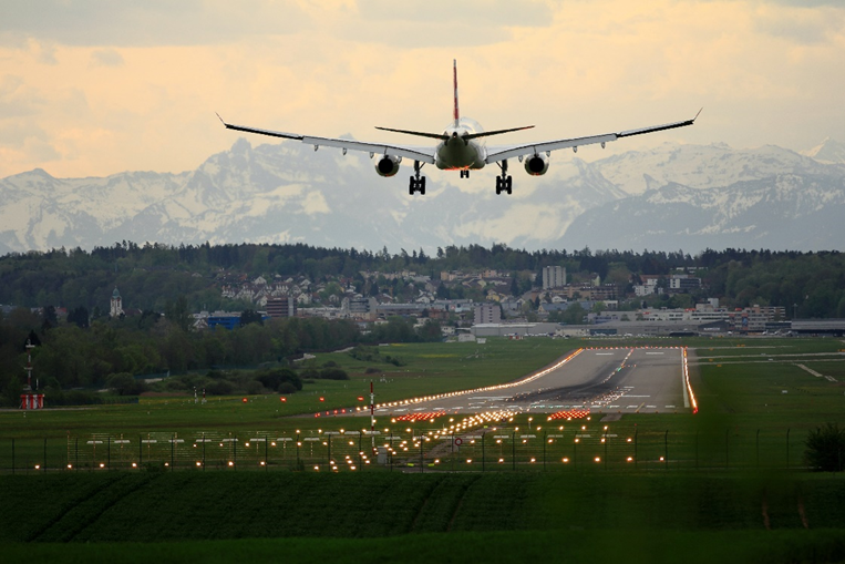 A plane landing on a runway with mountains in the distance