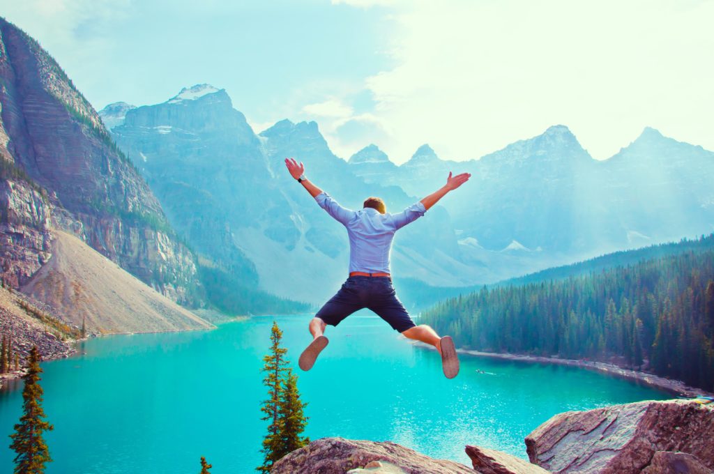 A man jumping of a cliff into a mountain lake