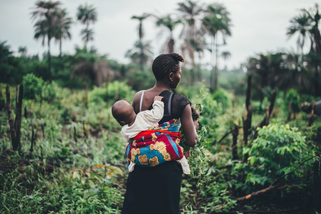 A woman working in the fields with a baby on her back