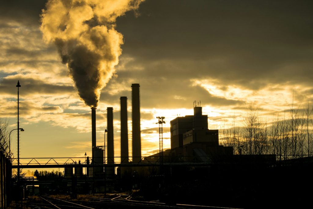 Smoking factory chimneys against a sunlit sky