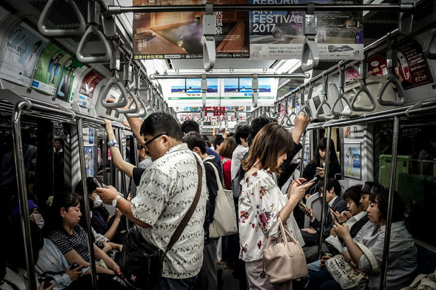 A busy commuter train where everyone is on their mobile phone