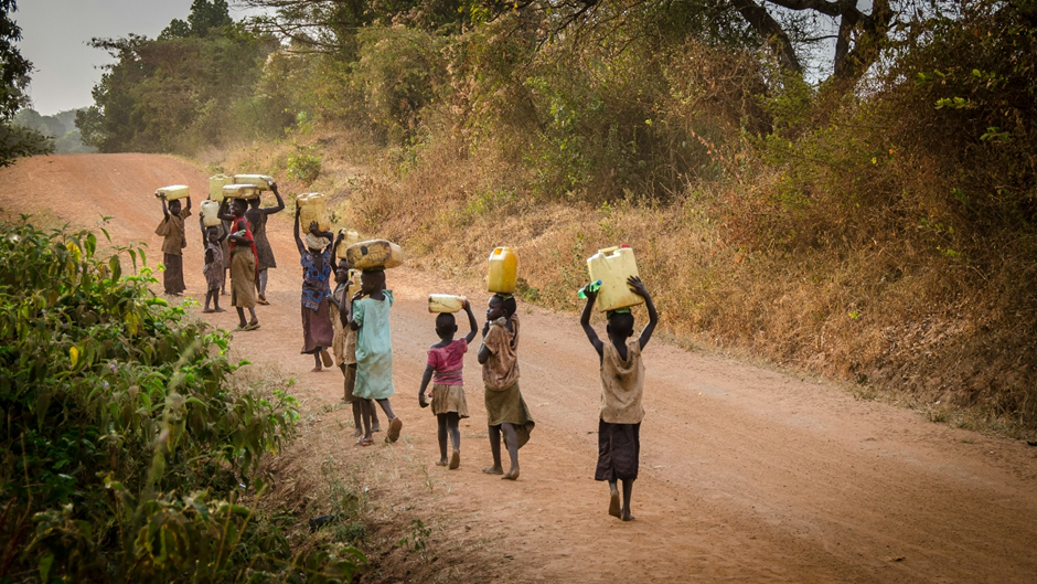 A group of Africans walking along a track with containers for water on their heads