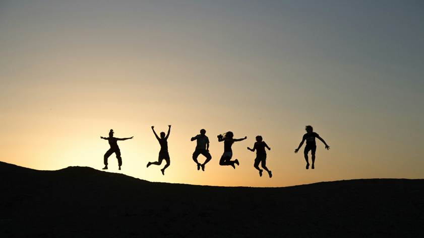 The silhouettes of several people jumping for joy