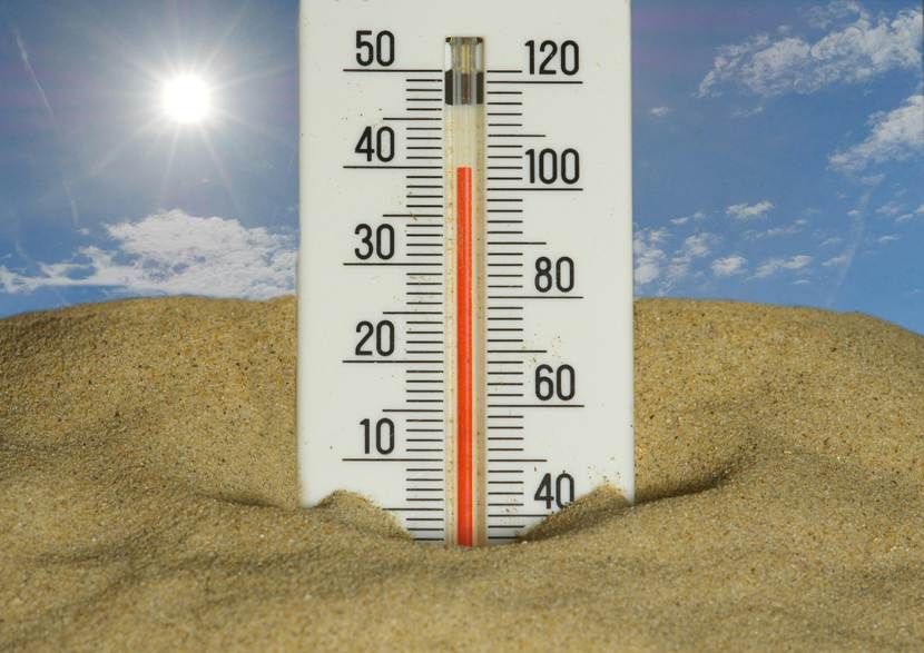 A thermometer showing 40 degrees C in front of a desert scene 