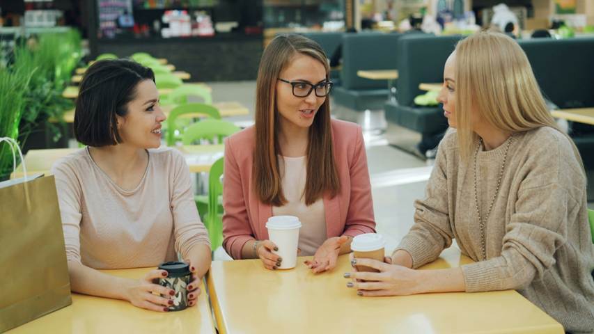 Three young women talking in a coffee bar